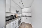 White fitted kitchen with integrated oven, worktops and storage cupboards.