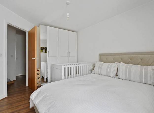 Bedroom with bed, wardrobe, door, and wooden floor.
