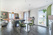 Open-plan living area with dining table, chairs, and balcony doors.