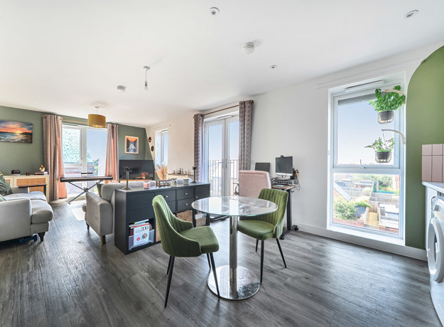 Open-plan living area with dining table, chairs, and balcony doors.