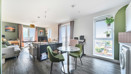 Open-plan living area with dining table, chairs, and balcony doors.