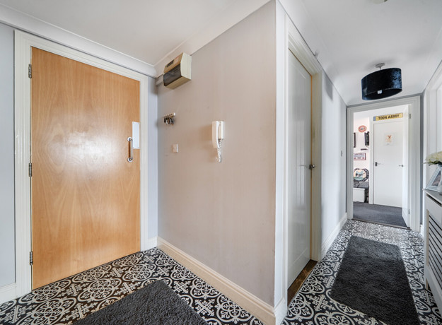 Entrance hallway with wooden door and patterned flooring.