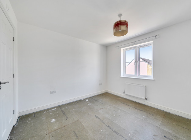 Empty bedroom with window and radiator.