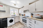 Kitchen with white cabinets, appliances, countertop workspace and a window.
