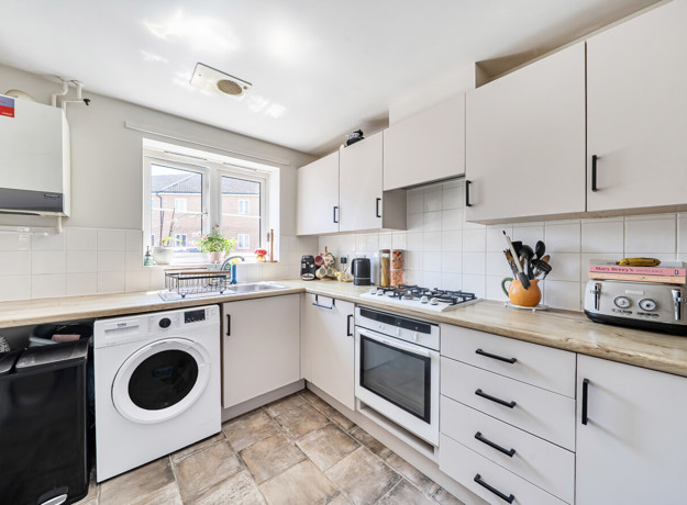 Kitchen with white cabinets, appliances, countertop workspace and a window.