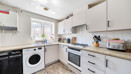 Kitchen with white cabinets, appliances, countertop workspace and a window.