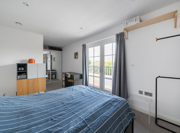 Bedroom with a double bed, wardrobe and balcony doors.
