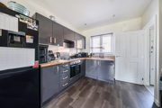 Kitchen with fitted units, appliances, window and a wood-effect flooring.
