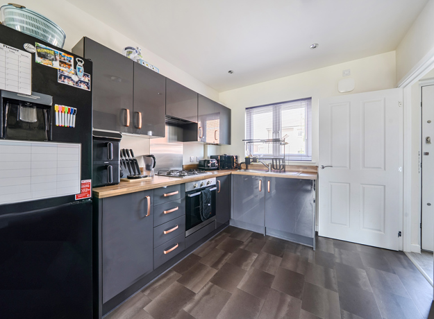 Kitchen with fitted units, appliances, window and a wood-effect flooring.