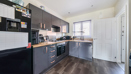 Kitchen with fitted units, appliances, window and a wood-effect flooring.