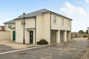 Exterior view of building with garages and paved forecourt in a residential area.