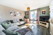 Living room with corner sofa, television, window and framed wall pictures.