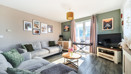 Living room with corner sofa, television, window and framed wall pictures.