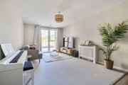 Living room with sofa, piano, television, rug, plant and window.