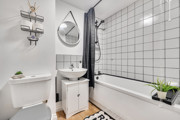 Bathroom with bathtub, shower, toilet, sink and tiled wall.