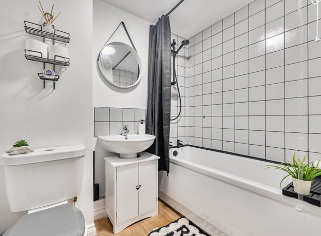 Bathroom with bathtub, shower, toilet, sink and tiled wall.