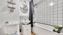 Bathroom with bathtub, shower, toilet, sink and tiled wall.