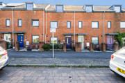 Brick terraced townhouses with on-street parking and pavement in a residential area