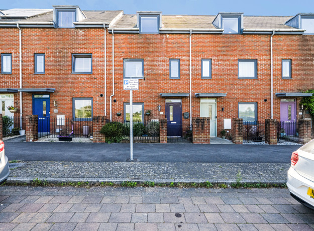 Brick terraced townhouses with on-street parking and pavement in a residential area