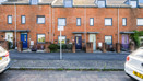 Brick terraced townhouses with on-street parking and pavement in a residential area