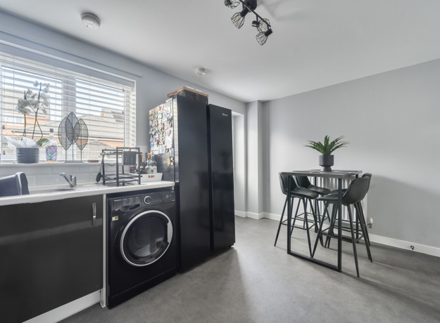 Kitchen view with counter, washing machine, and window with blinds.