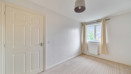 Empty bedroom with carpeted floor, light walls, and window with curtains.