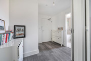 Hallway with shelving unit, shoe cabinet and doorway to another room.