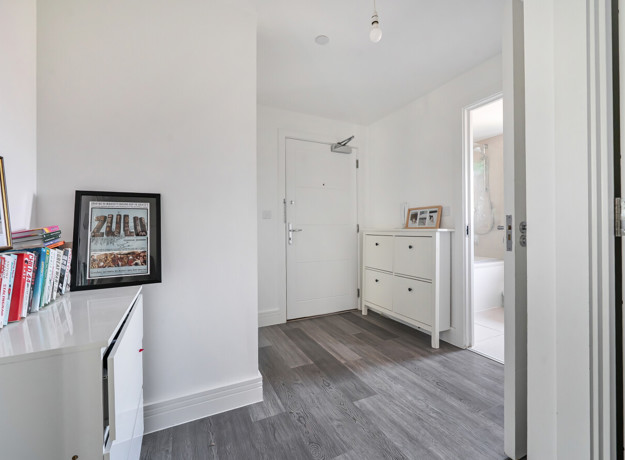 Hallway with shelving unit, shoe cabinet and doorway to another room.