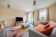 Living room with sofa, TV unit, patterned rug, french doors and large window