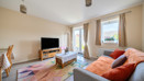 Living room with sofa, TV unit, patterned rug, french doors and large window