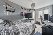 Bedroom with bed, desk setup, shelves and window with natural light.