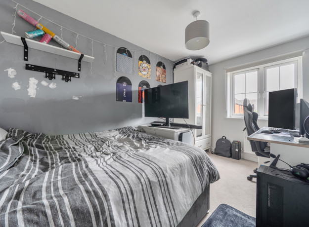 Bedroom with bed, desk setup, shelves and window with natural light.