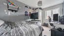 Bedroom with bed, desk setup, shelves and window with natural light.