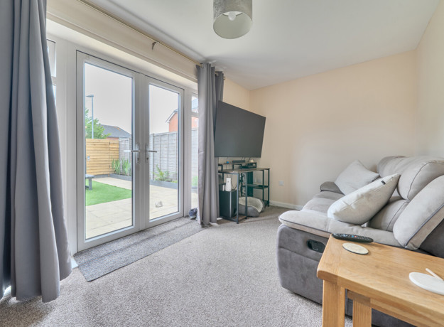 Living room with sofa, glass doors to garden and neutral decor.