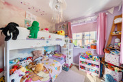 Children's bedroom with bunk bed, toys, shelving, pink walls and window.