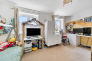 Bedroom with child's bed, TV, storage units, desk with PC screen and windows.