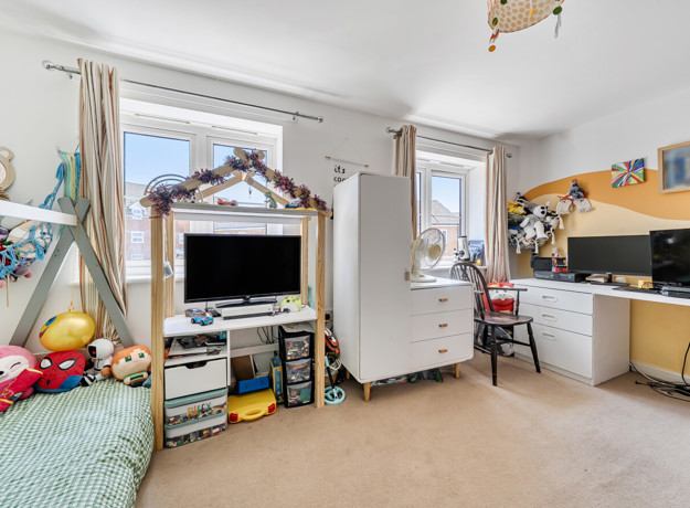 Bedroom with child's bed, TV, storage units, desk with PC screen and windows.
