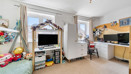 Bedroom with child's bed, TV, storage units, desk with PC screen and windows.