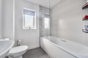 Bathroom with bathtub, toilet, sink, and tiled walls.