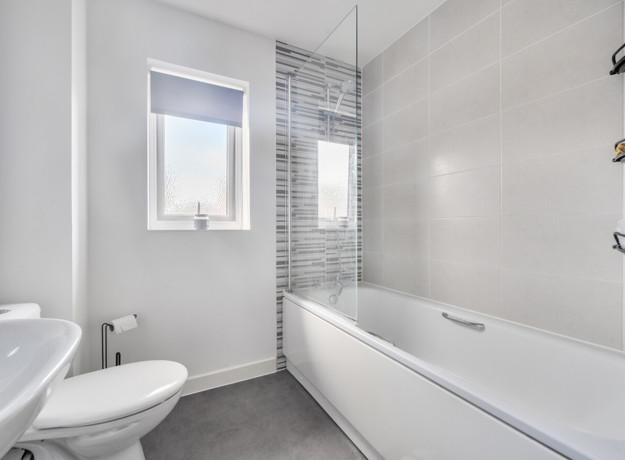 Bathroom with bathtub, toilet, sink, and tiled walls.