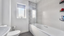 Bathroom with bathtub, toilet, sink, and tiled walls.