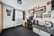 Room with desk, shelving, sofa and framed pictures on the wall.