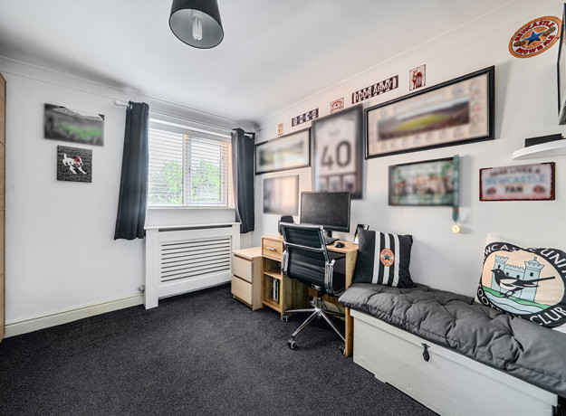 Room with desk, shelving, sofa and framed pictures on the wall.