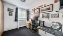 Room with desk, shelving, sofa and framed pictures on the wall.