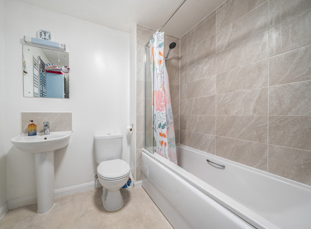 Bathroom with bathtub, shower, toilet, sink, and wall mirror.