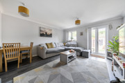 Living room with sofa, rug, dining table, and patio doors to the garden.
