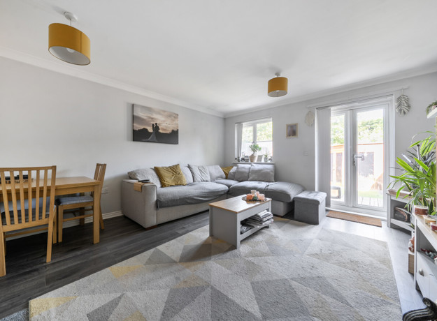 Living room with sofa, rug, dining table, and patio doors to the garden.