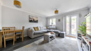 Living room with sofa, rug, dining table, and patio doors to the garden.