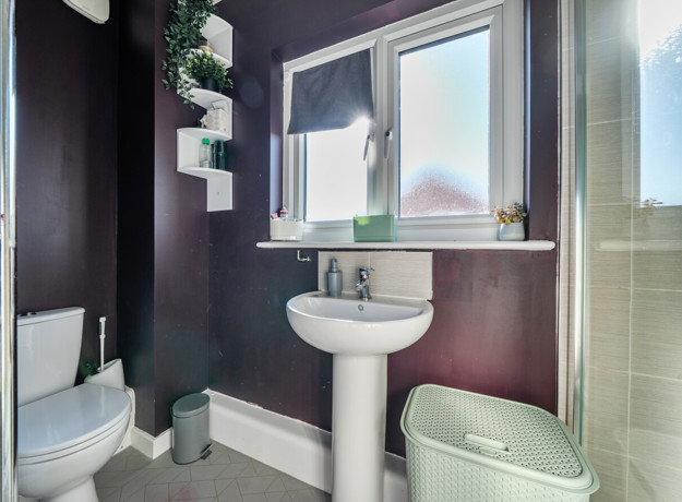 Bathroom with sink, toilet, shower enclosure and window.