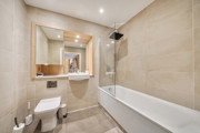 Bathroom with bathtub, shower, toilet, sink, and wall mirror.